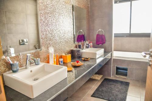 y baño con lavabo, espejo y bañera. en SUPERBE VILLA AVEC PISCINE PLAGES DES NATIONS en Rabat