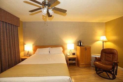 a bedroom with a bed and a ceiling fan and a chair at Motel Grand-Pré Inc in Bonaventure