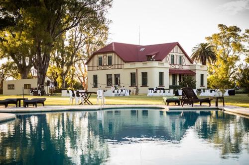 une maison avec une piscine en face d'une maison dans l'établissement Hotel Rural La Pampeana, à Sarah