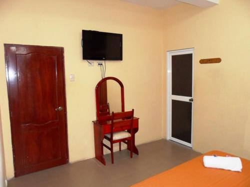 Habitación con silla y TV en la pared. en Hotel Jira, en Guayaquil