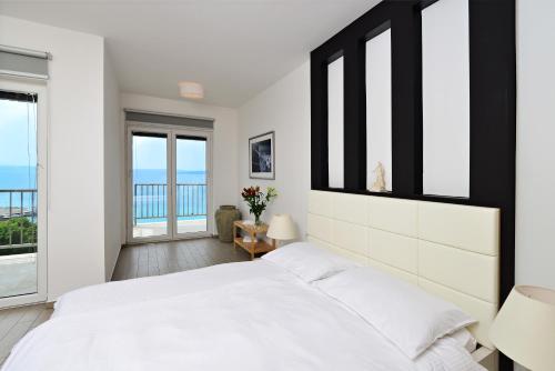 a white bedroom with a large bed and windows at Villa Mar - Only 50m To The Beach in Stara Baška