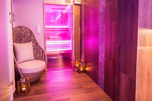 a hallway with a chair and pink lighting in a room at Willa Ostoja Wellness in Świeradów-Zdrój