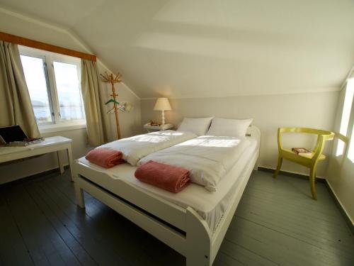 ein weißes Bett in einem Zimmer mit einem Schreibtisch und einem Fenster in der Unterkunft Atlantic View Lofoten in Bøstad