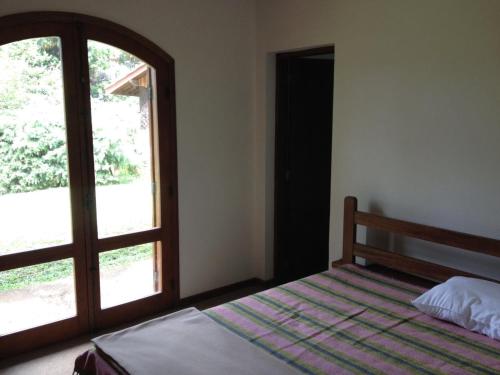 a bedroom with a bed and a large window at Casa do sol in Monte Verde