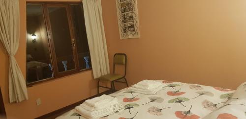 a bedroom with a bed and a chair and a window at Hostal Utama in Comunidad Yumani