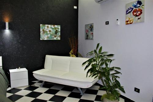 ein weißes Sofa in einem Zimmer mit kariertem Boden in der Unterkunft Il cortiletto in Ravanusa