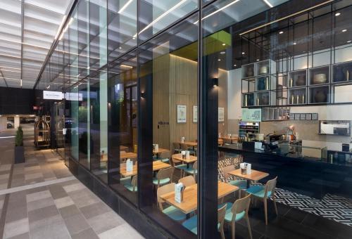 a restaurant with wooden tables and chairs and glass walls at Novotel Melbourne Central in Melbourne