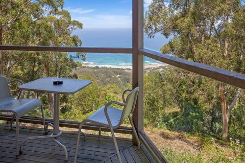 a table and chairs on a deck with a view of the ocean at Beacon Point Ocean View Villas in Apollo Bay
