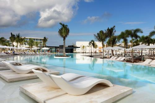 
a hotel room with a pool, chairs, and tables at Grand Palladium Costa Mujeres Resort & Spa - All Inclusive in Cancún
