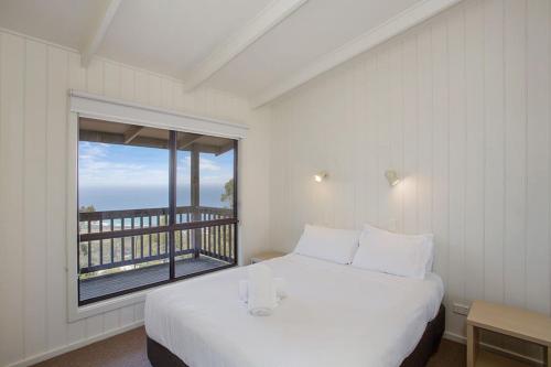 a bedroom with a bed and a large window at Beacon Point Ocean View Villas in Apollo Bay