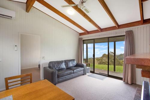 a living room with a couch and a large window at Beacon Point Ocean View Villas in Apollo Bay
