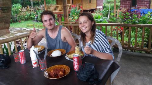 a man and a woman sitting at a table eating food at Ariel Bungalow Tetebatu in Tetebatu