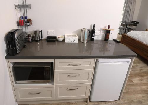 a kitchen with a counter with a microwave and a refrigerator at Lot113 Vineyard Accommodation in Upper Swan