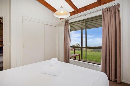 a bedroom with a white bed and a large window at Beacon Point Ocean View Villas in Apollo Bay