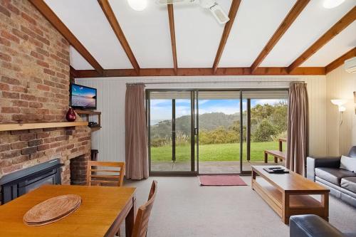 a living room with a table and a fireplace at Beacon Point Ocean View Villas in Apollo Bay