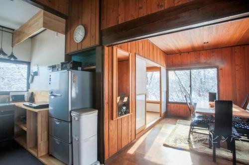 a kitchen with a refrigerator and a table with a desk at Lucky Duck Cabin in Akakura