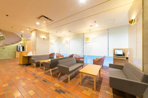a lobby with couches and chairs and a television at Hotel S-Plus Hiroshima Peace Park in Hiroshima
