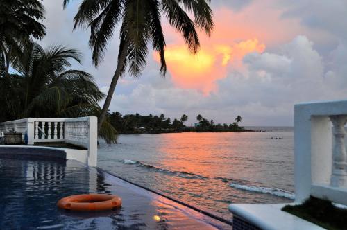 a pool with a view of the ocean and a sunset at Hotel Casa Canada in Big Corn Island