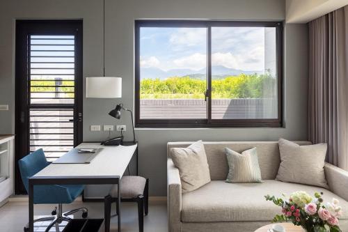 ein Wohnzimmer mit einem Sofa, einem Schreibtisch und einem Fenster in der Unterkunft Jolley Hotel in Taipeh