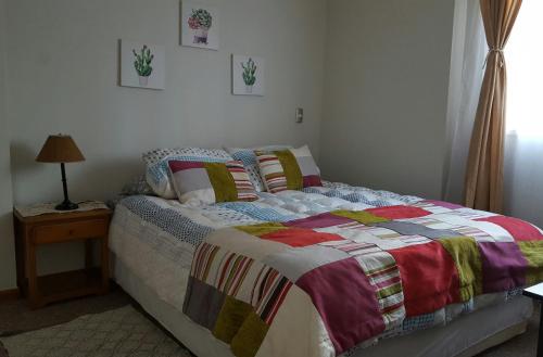 a bedroom with a bed with a colorful quilt on it at Aparments R&G Puerto Montt in Puerto Montt