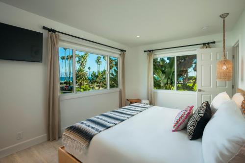 1 Schlafzimmer mit einem weißen Bett und 2 Fenstern in der Unterkunft Blue Sands Inn, A Kirkwood Collection Hotel in Santa Barbara