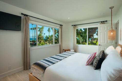 a bedroom with a white bed and two windows at Blue Sands Inn, A Kirkwood Collection Hotel in Santa Barbara