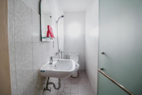 La salle de bains blanche est pourvue d'un lavabo et de toilettes. dans l'établissement RedDoorz @ Pandu Raya Bogor, à Bogor