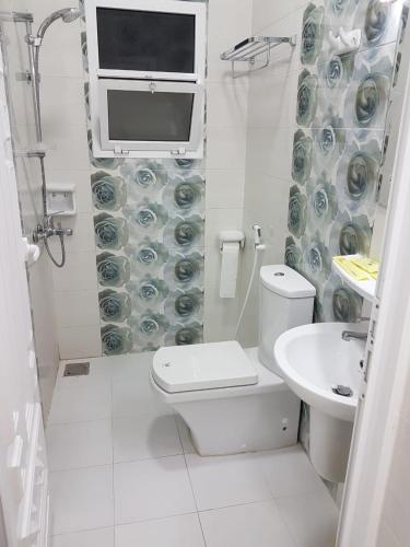 a white bathroom with a toilet and a sink at Orient Apartments in Nizwa