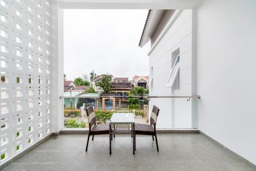 un balcone con tavolo e sedie e una grande finestra di Chi Thanh Villa a Hoi An