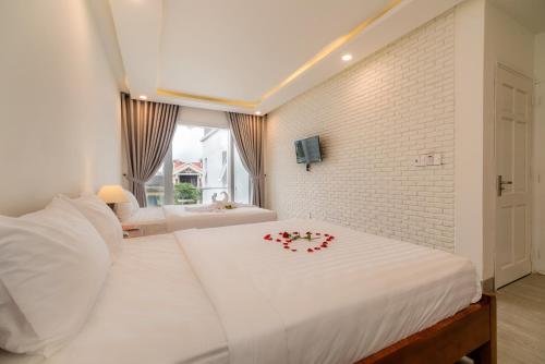 a bedroom with a white bed with a flower on it at Chi Thanh Villa in Hoi An
