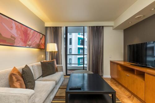 a living room with a couch and a tv at Chatrium Sathon Bangkok in Bangkok