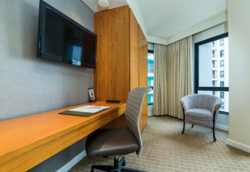a room with a desk with a television and a chair at Chatrium Sathon Bangkok in Bangkok