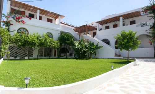 un bâtiment avec une cour verdoyante devant lui dans l'établissement Rubini Rooms, à Parikia