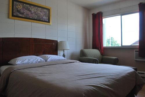 a bedroom with a bed and a chair and a window at Value Lodge Motel in Nanaimo