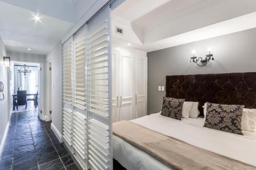 a bedroom with white walls and a bed with a headboard at Romney Park Luxury Apartments by The Stay Collection in Cape Town