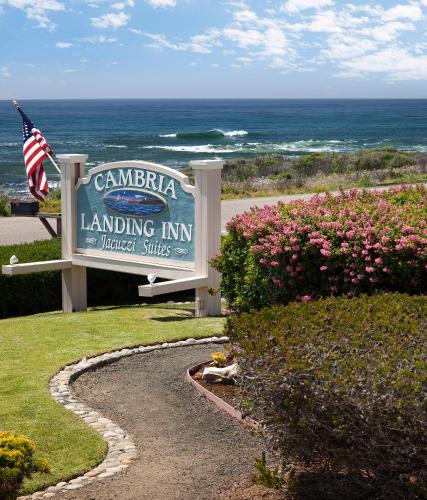 a sign for the landing inn with the ocean in the background at Cambria Landing Inn and Suites in Cambria