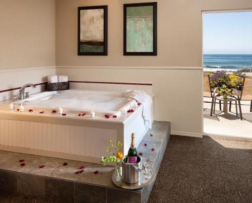 a bath tub in a room with a view of the ocean at Cambria Landing Inn and Suites in Cambria