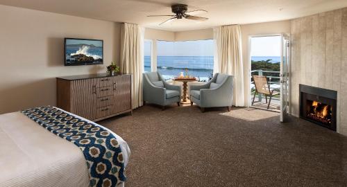 a bedroom with a bed and a fireplace and a table with chairs at Cambria Landing Inn and Suites in Cambria