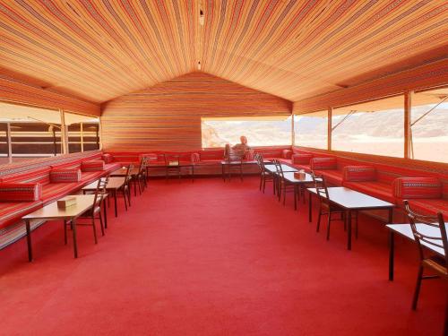 a room with red chairs and tables and a person at Real Bedouin Experience Tours & Camp in Wadi Rum