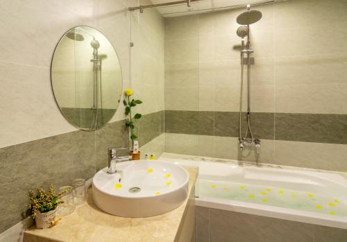 a bathroom with a sink and a tub and a mirror at Happy Day Hotel & Spa in Danang