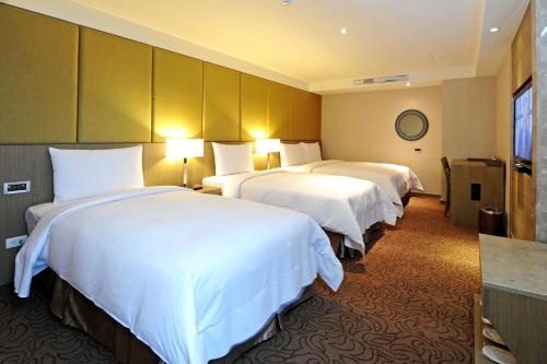 a hotel room with two beds with white sheets at International Citizen Hotel in Kaohsiung