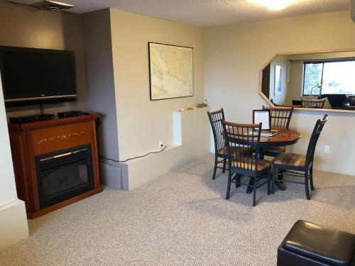 sala de estar con mesa, sillas y TV en Sunshine Coast Suites en Sechelt