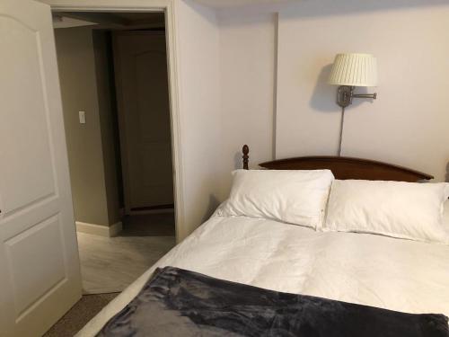 ein Bett mit weißer Bettwäsche und einer Lampe in einem Zimmer in der Unterkunft Sunshine Coast Suites in Sechelt