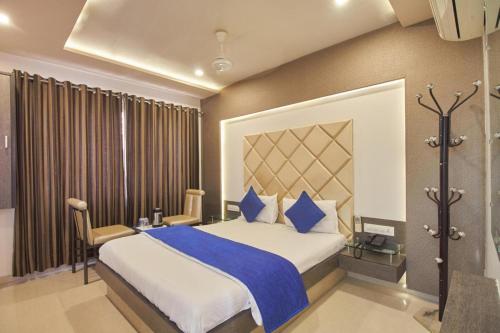 a bedroom with a large bed with blue pillows at Hotel Flair Inn in Ahmedabad