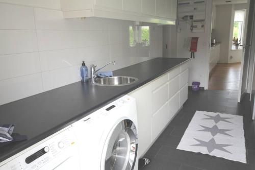 a kitchen with a washing machine and a sink at Poolvilla i Höllviken in Höllviken
