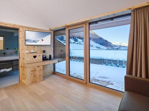 a room with large windows with a view of snow covered mountains at Alpeiner - Nature Resort Tirol in Neustift im Stubaital
