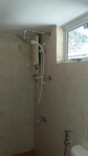 a shower in a bathroom with a toilet and a window at Mini's Residence in Colombo