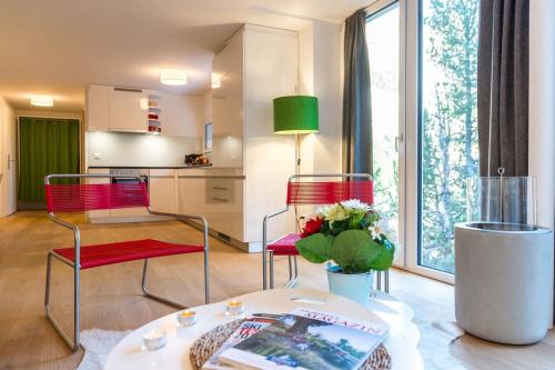 a living room with red chairs and a table and a kitchen at Legendär Zermatt in Zermatt