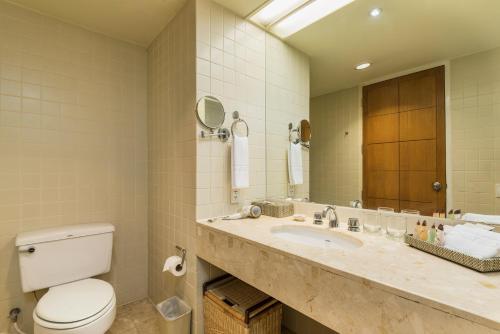 a bathroom with a toilet and a sink and a mirror at Chatrium Sathon Bangkok in Bangkok