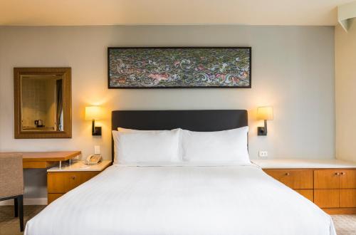 a bedroom with a large white bed and a desk at Chatrium Sathon Bangkok in Bangkok